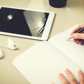 Tablet, auricolari ed un quaderno a quadretti