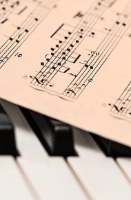 Spartito musicale posto sopra la tastiera di un pianoforte